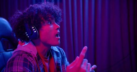 Young man gamer wearing headphones, expressing surprise