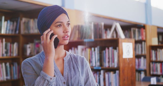 Young Woman Wearing Headscarf Talking on Phone in Library - Download Free Stock Images Pikwizard.com