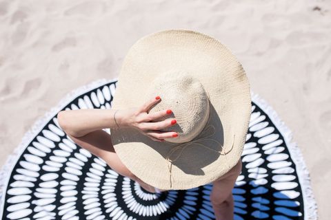Summer Beach Sunbathing with Stylish Hat and Vibrant Nail Polish
