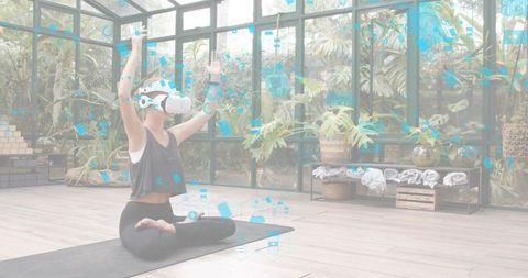 Practicing virtual reality yoga in glass conservatory with lush plants and digital overlays