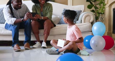 Family Celebrating Child's Birthday with Gift Unwrapping at Home