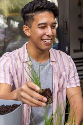 Young man enjoying gardening on modern patio with planters