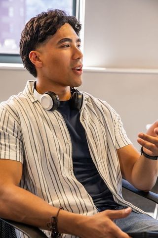 Young asian man speaking and gesturing in modern office casual meeting with headphones