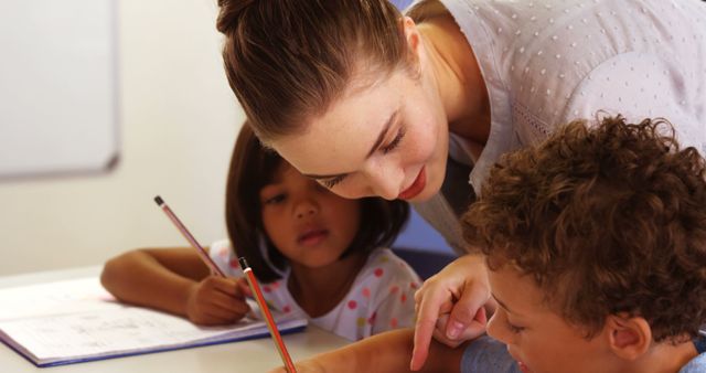 Teacher Helping Young Students with Homework in Classroom - Download Free Stock Images Pikwizard.com