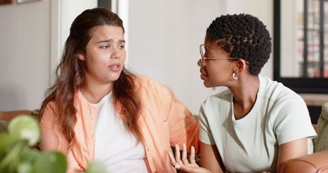 Two women having serious conversation on couch showing support, comfort and connection