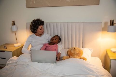 Mother and Daughter Sharing Quality Time with Laptop in Cozy Bedroom