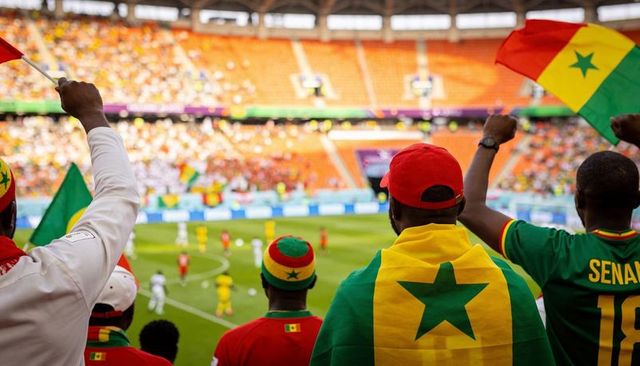 Senegal fans cheering in stadium waving flags and wearing team jerseys