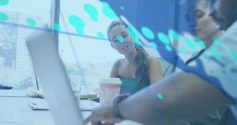 Young Professional Reviewing Laptop with Colleagues and Digital Data Overlay in Office