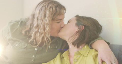 Affectionate Portrait of Loving Female Couple Sharing a Kiss on Sofa
