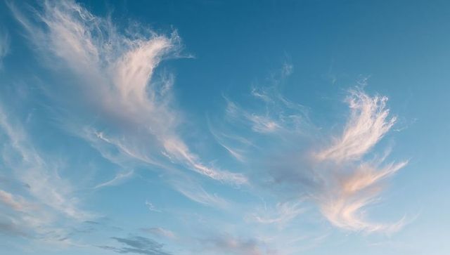 Drifting Wispy Cirrus Clouds at Sunset Showing Pink and Golden Hues over Ethereal Blue Sky