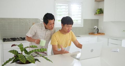 Father and son enjoying laptop time in modern kitchen
