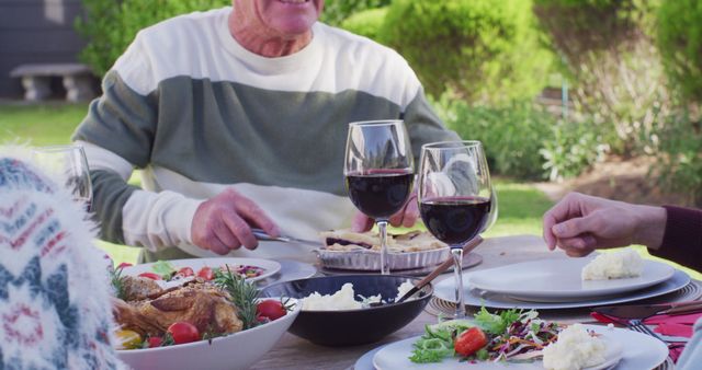 Family dinning at al fresco table in garden with fresh food and wine, suggesting use for articles on family gatherings, outdoor dining, healthy lifestyle, and summer food ideas. Ideal for promoting family-friendly recipes, picnic spaces, or patio garden inspiration.