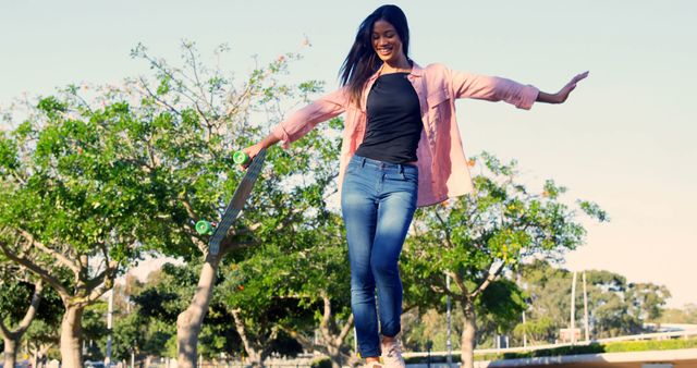 Young woman balancing skateboard joyfully outdoors in park - Download Free Stock Images Pikwizard.com