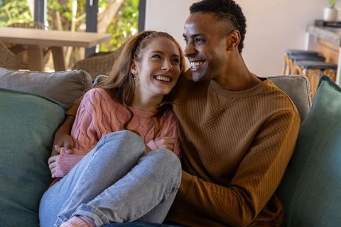 Diverse couple enjoying cozy moment on sofa in modern living room
