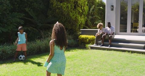 Family Watching Children Play Soccer in Lush Backyard