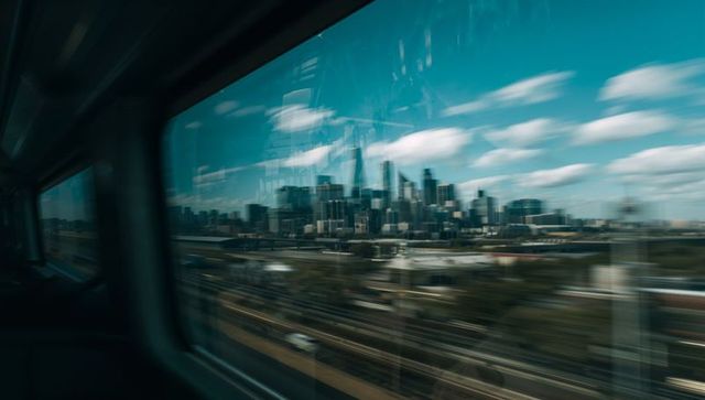 Racing past urban skyline through train window with motion blur, glass reflections