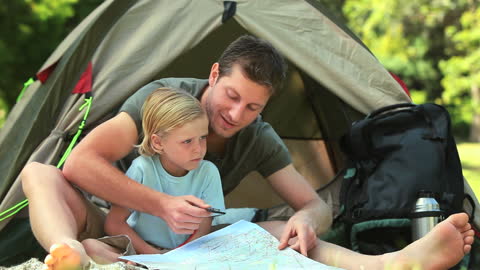Father Teaching Son to Read Map During Camping Adventure