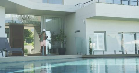 Mature man talking on phone by minimalist luxury pool terrace, relaxed summer lifestyle