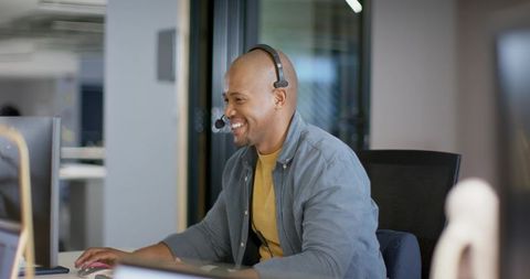 African American Support Agent Smiling on Headset While Working at Modern Office Desk
