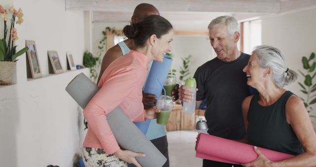 Group of senior adults smiling and chatting after yoga session at home, holding yoga mats and drinking smoothies; represents fitness, friendship, and healthy lifestyle. Ideal for wellness blogs, senior fitness programs, and health promotions.