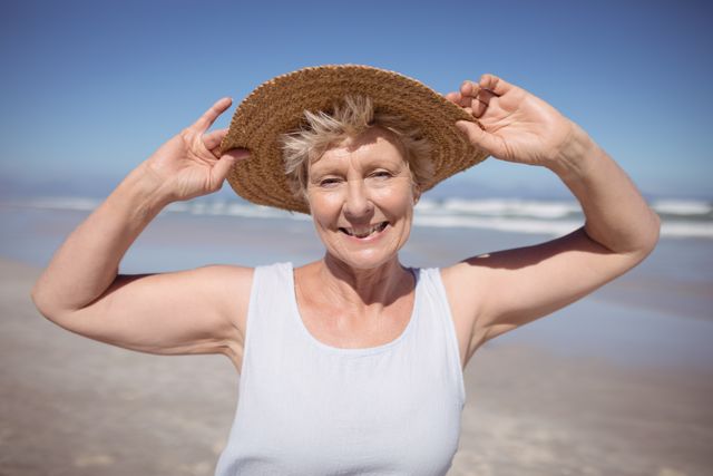 Portrait of senior woman wearing sun hat at beach during sunny day