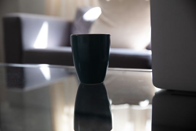 Close up of a cup on a table with a couch in the background, Domestic life. 
