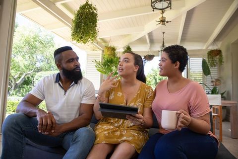 Diverse Friends Chatting Outdoors Sharing Tablet by Garden