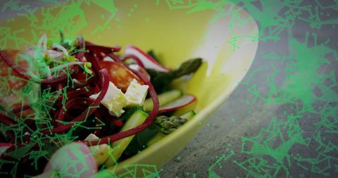 Colorful mediterranean vegetable salad in yellow bowl with asparagus feta and beet spirals