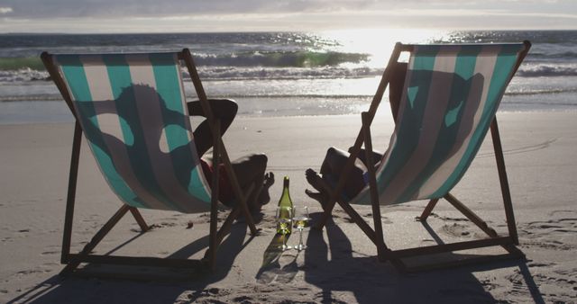 African american couple relaxing in deck chairs admiring the view on the beach. holiday and healthy outdoor leisure time by the sea.