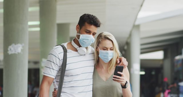 Diverse Couple Wearing Face Masks Checking Phone in Public Space - Download Free Stock Images Pikwizard.com