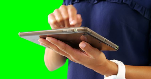 Person using a tablet with a green screen background, commonly used for editing or overlay purposes. This image can be utilized for tech tutorials, app demonstrations, digital marketing content, or e-learning materials.