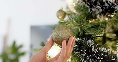 Decorating Christmas Tree with Gold Baubles and Silver Tinsel