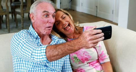 Joyful Senior Couple Laughing While Taking Selfie at Home