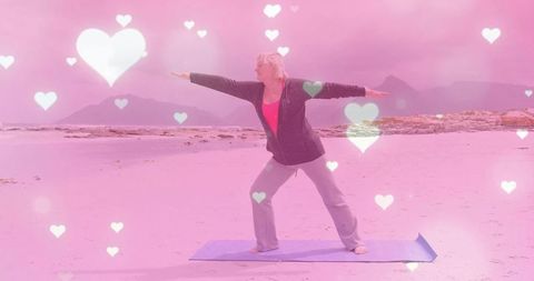 Senior woman practicing warrior ii pose on tranquil beach