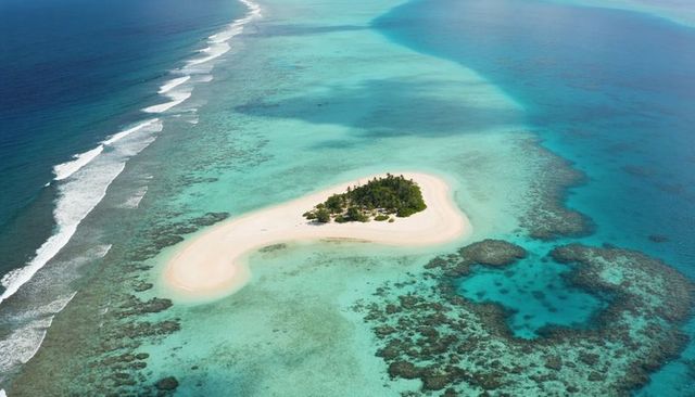Revealing crescent sandbar curving around turquoise lagoon with palm-covered islet