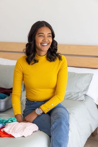 Woman packing clothes for journey with bright smile