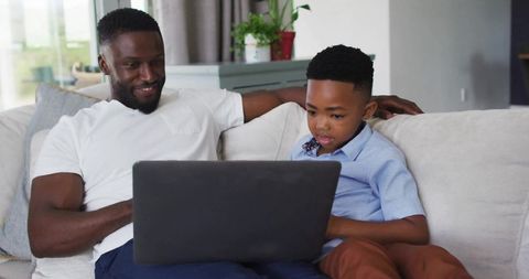 Father and Son Using Laptop in Cozy Living Room for Quality Time