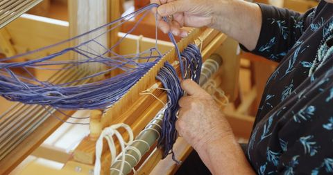 Senior Woman Weaving Artisanship on Wooden Loom