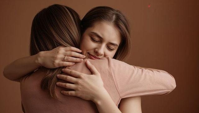 Two women embracing in warm brown tones sharing comfort, intimacy and close friendship