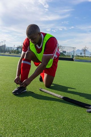 Athlete Tying Cleats on Turf Field During Hockey Training