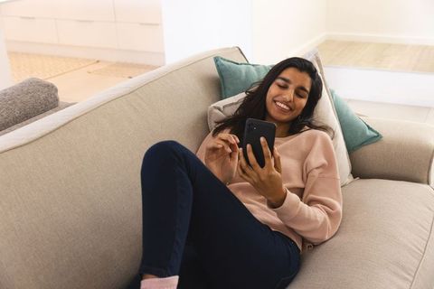 Woman Relaxing on Sofa Using Smartphone in Minimalist Living Room