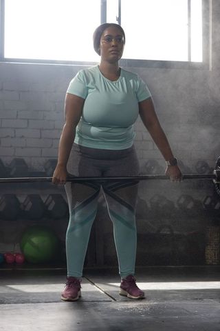 Deadlifting african american woman in teal activewear, focused strength training, gym