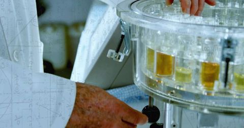 Senior technician loading rotary carousel of amber vials, adjusting knob for lab samples