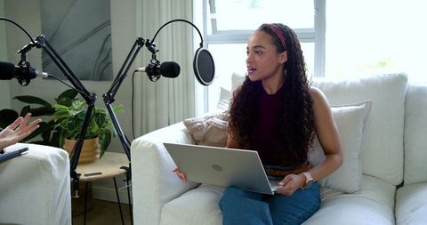 Host recording podcast at home with laptop, boom microphones and casual living room vibe