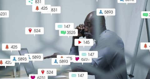 Executive juggling smartphone and laptop while handling flood of social media notifications