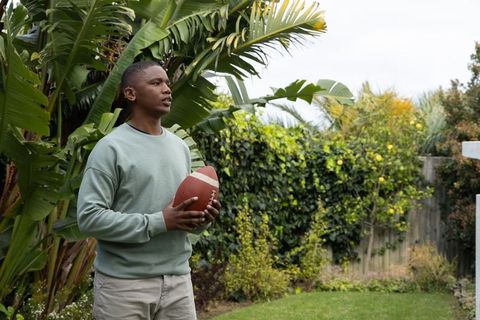 African american teen holding football in tropical backyard casual outdoor lifestyle youth