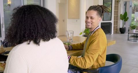 Diverse friends sharing salad and laughter at sunlit modern kitchen island