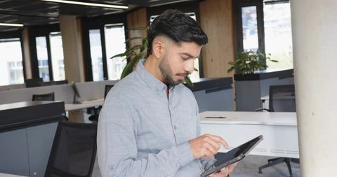 Focused Businessman Tapping on Tablet in Modern Office