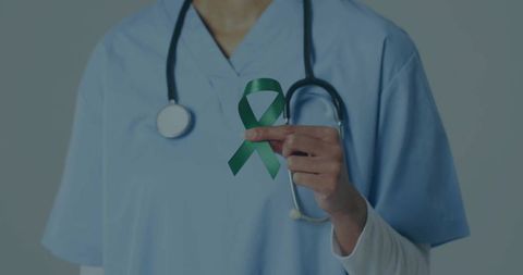 Nurse Holding Green Awareness Ribbon Wearing Blue Scrubs and Stethoscope for Mental Health