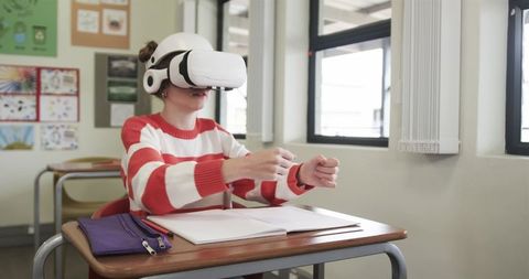 Girl Wearing VR Headset in Classroom Studying with Notebook